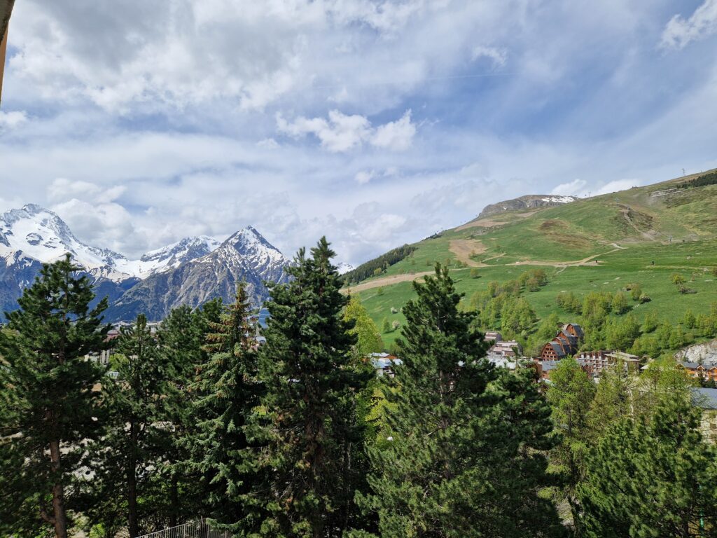 Image montrant de gauche à droite la Muzelle, L'aiguille de Venosc et la Dame Blanche. La Dame blanche, entre 1600 et 200m d'altitude est verte en ce printemps 2024 aux Deux Alpes